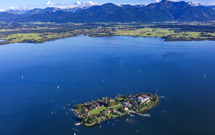 Luftaufnahme der Fraueninsel im Chiemsee mit Alpen im Hintergrund.