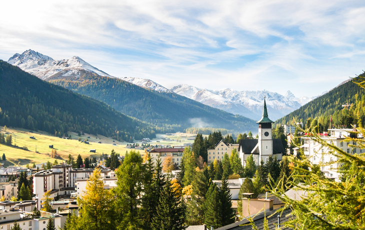 Blick auf Davos im Herbst mit Kirche und Alpen im Hintergrund