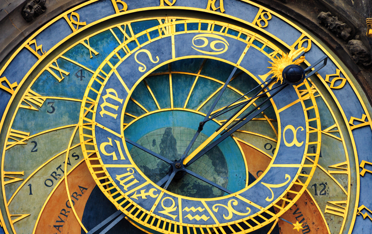 Nahaufnahme einer astronomischen Uhr mit Tierkreiszeichen und römischen Ziffern.