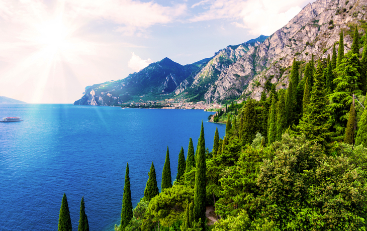 Blick auf Bardolino am Gardasee mit türkisblauem Wasser und Bergen im Hintergrund.