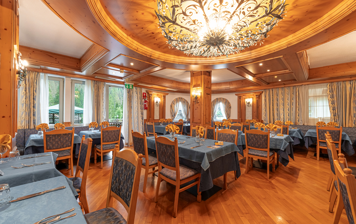 Elegantes Restaurant mit Holzdetails, blauen Tischdecken und dekorativer Deckenleuchte.