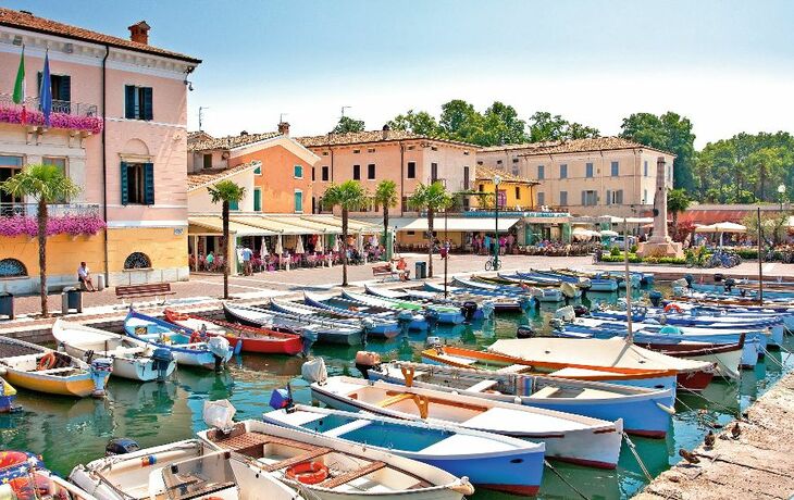 Hafen von Bardolino am Gardasee mit Booten, Häusern und blauem Himmel.