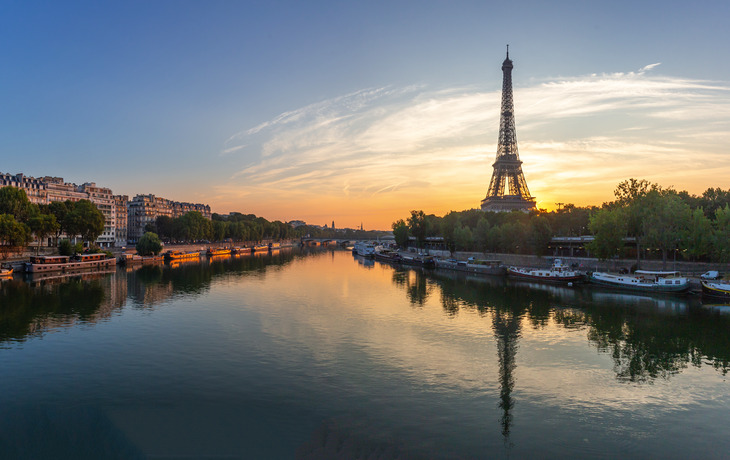 Eiffelturm in Paris bei Sonnenuntergang, Fluss im Vordergrund.