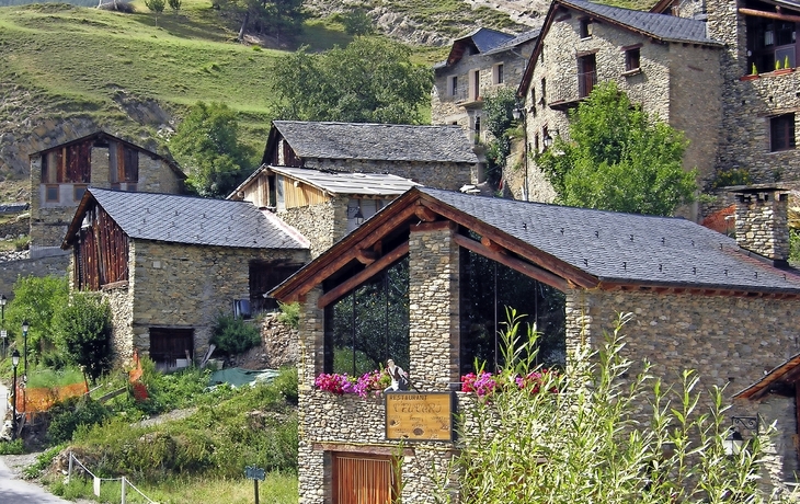 Steinhäuser in der ländlichen Gegend von Pal, Andorra, umgeben von grünen Hügeln.