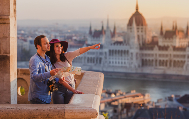 Touristenpaar in Budapest vor dem Parlamentsgebäude an der Donau.