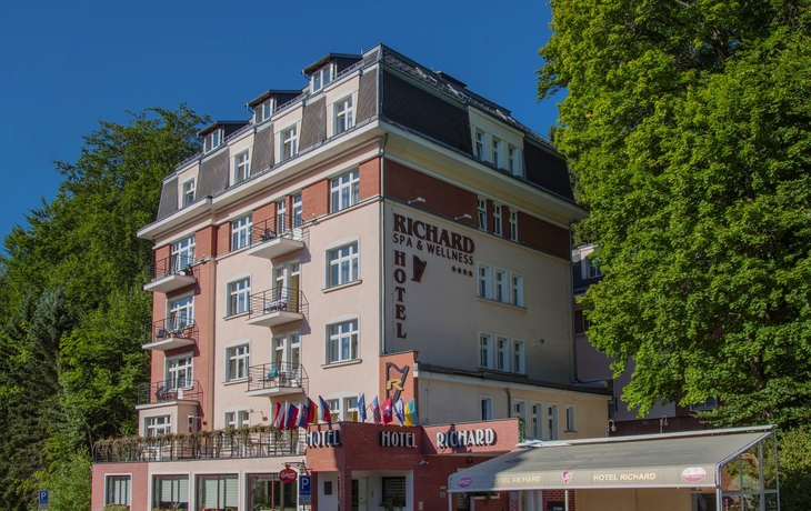 Außenansicht des Hotels Richard in Marienbad mit Balkonen und Bäumen im Hintergrund.