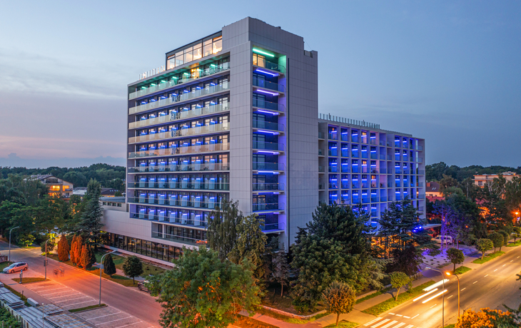 Hotelgebäude Olymp IV bei Dämmerung, beleuchtet, Außenansicht.