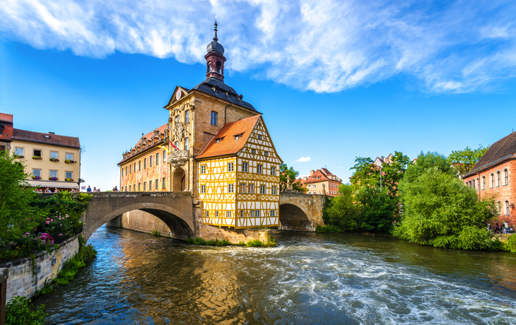 Fachwerkhaus auf Brücke über Fluss bei blauem Himmel.