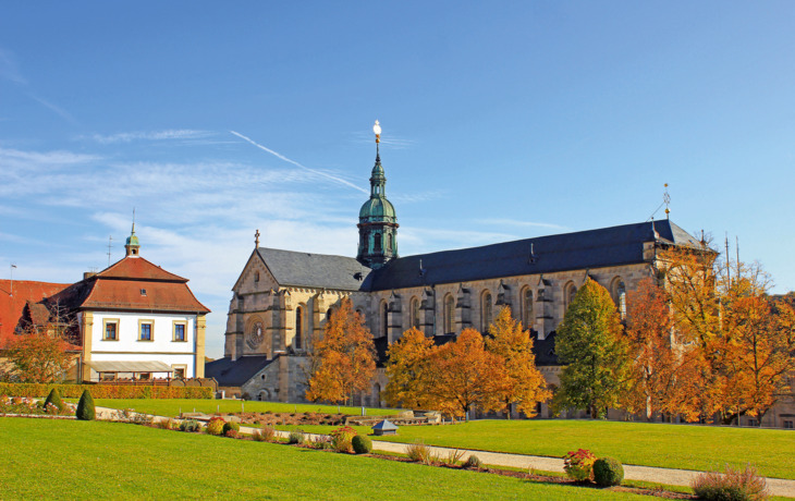 Historische Klosteranlage mit Herbstbäumen und blauem Himmel.