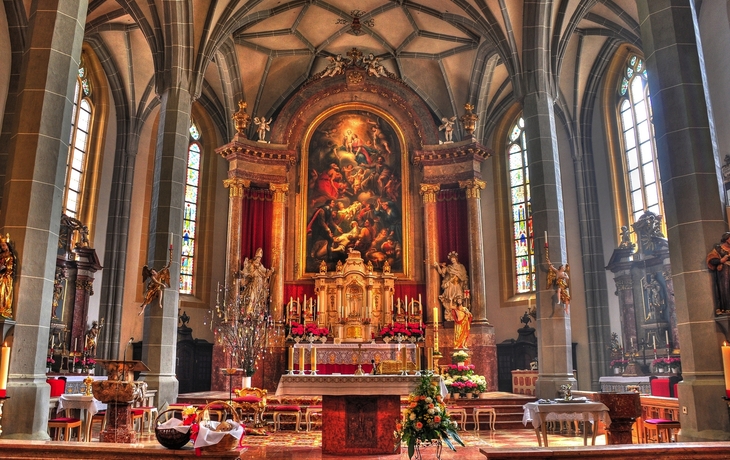 Innenansicht einer reich dekorierten Kirche mit Altar und Gemälden.
