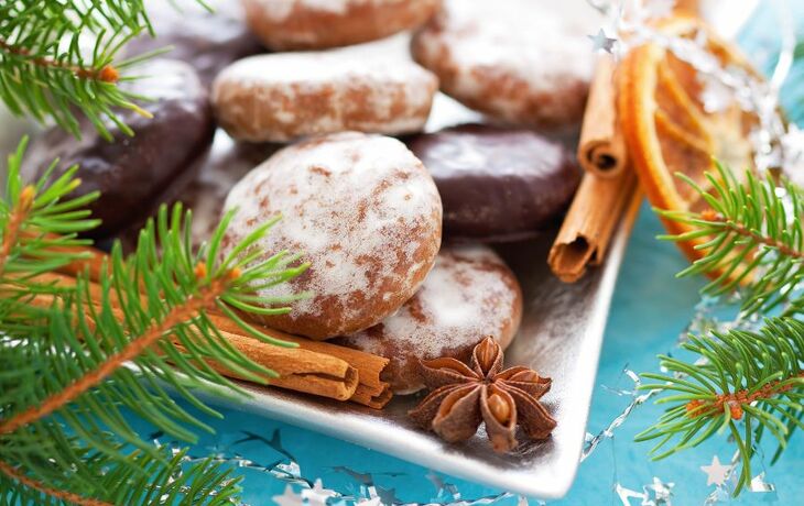 Lebkuchen, Zimtstangen und Anis auf einem Tablett mit weihnachtlicher Dekoration.