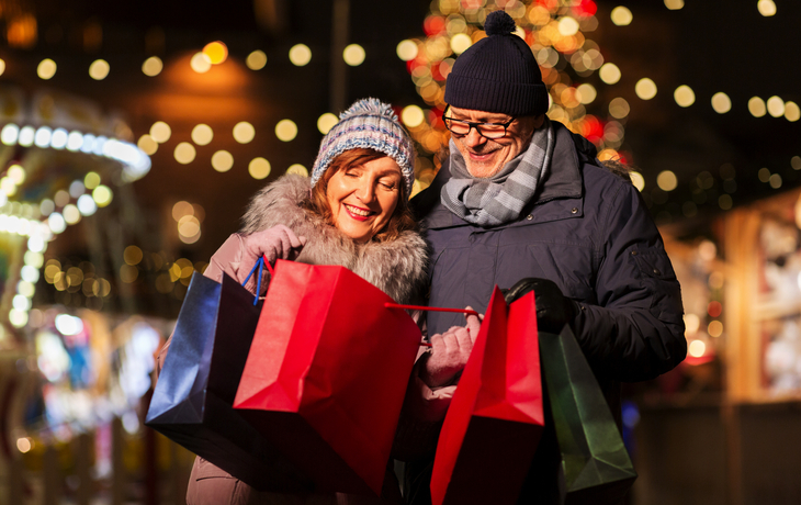 Paar beim Weihnachtseinkauf mit Einkaufstaschen im Freien.