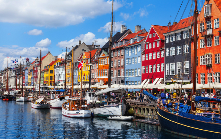 Bunte Häuser und Boote am Nyhavn in Kopenhagen, der Hauptstadt Dänemarks, bei sonnigem Wetter.