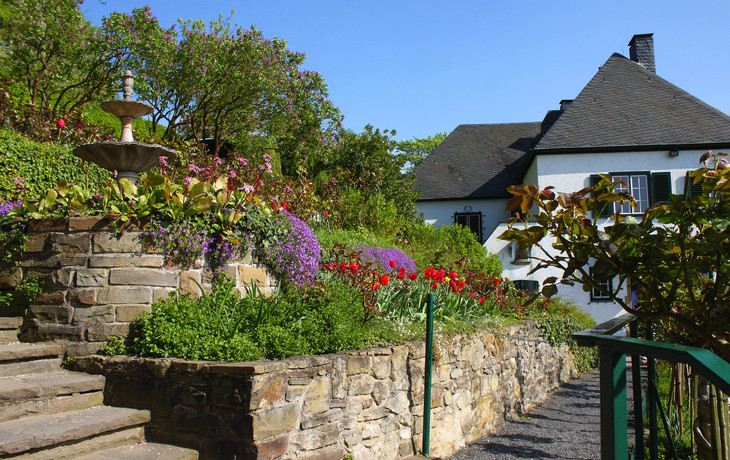 Gartenansicht des Wohnhauses von Konrad Adenauer in Bad Honnef, umgeben von Blumen.