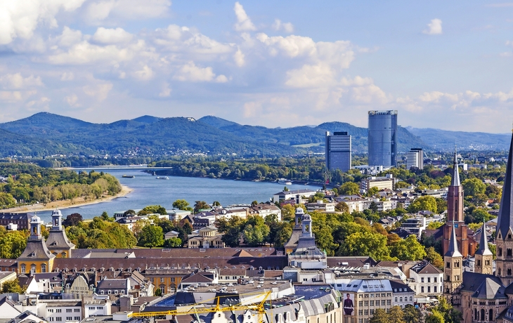 Panoramablick auf Bonn am Rhein mit Kirche und moderner Skyline bei sonnigem Wetter.