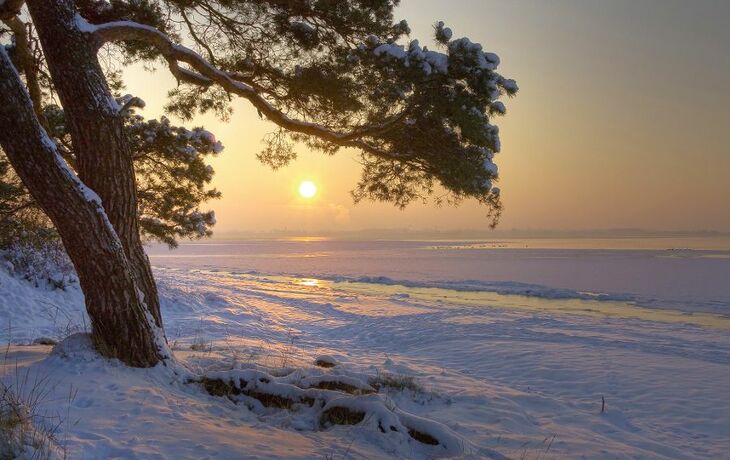 Schneebedeckter Strand an der Ostsee bei Sonnenuntergang im Winter.