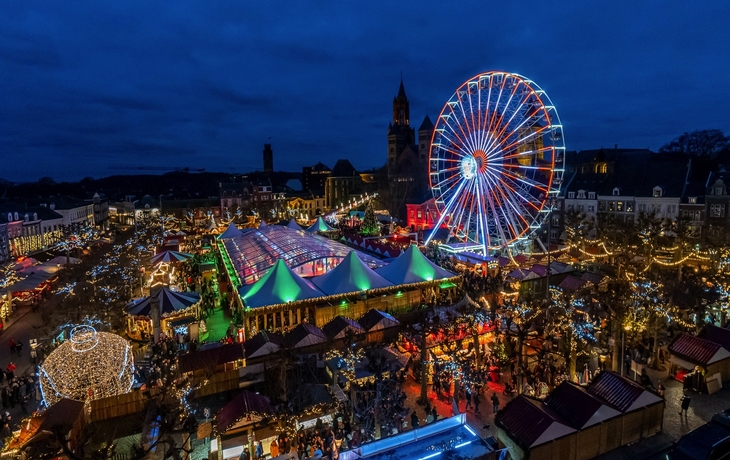 Weihnachtsmarkt in Maastricht bei Nacht mit beleuchtetem Riesenrad.