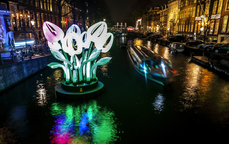 Beleuchtete Tulpeninstallation am Kanal in einer Stadt bei Nacht.