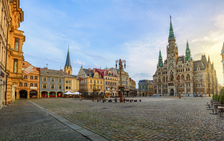 Historischer Platz mit Rathaus und alten Gebäuden bei Sonnenuntergang.