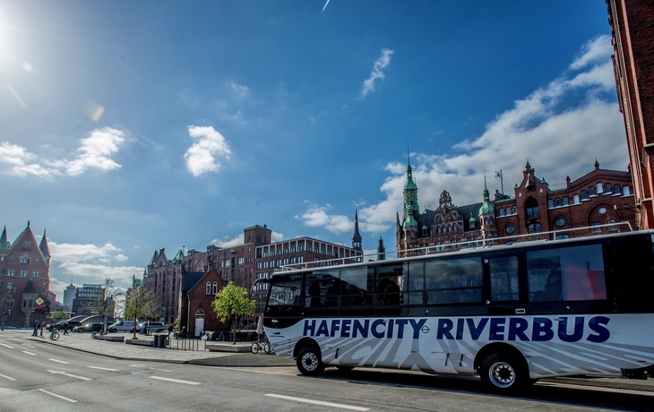 Hafencity Riverbus vor historischen Backsteingebäuden am Brooktorkai, blauer Himmel.