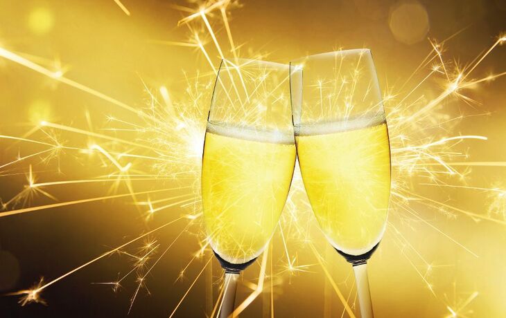 Zwei Champagnergläser vor funkelndem Feuerwerk.