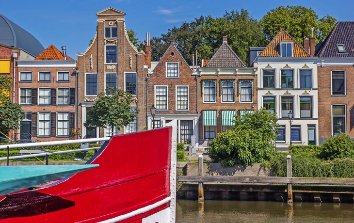 Kanal mit historischen Häusern und einem roten Boot im Vordergrund.
