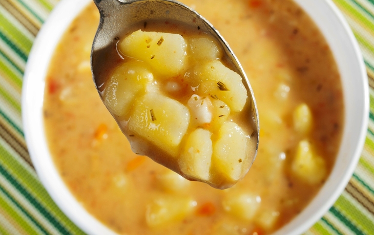 Löffel mit Kartoffelsuppe über einer Schüssel.
