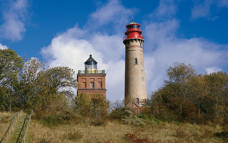 Zwei Leuchttürme auf Kap Arkona umgeben von Bäumen und einem Weg bei klarem Himmel.
