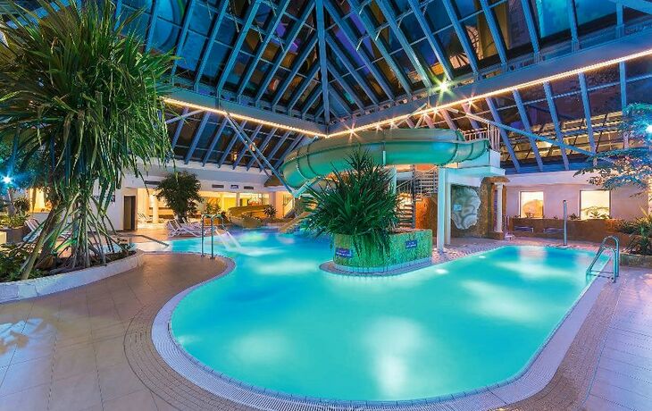 Innenaufnahme eines hellblauen Erlebnisbads mit Pool und Wasserrutsche im IFA Rügen Hotel.