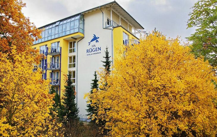 Gebäude des IFA Rügen Hotel und Ferienparks im Herbst, umgeben von Bäumen mit goldgelbem Laub.