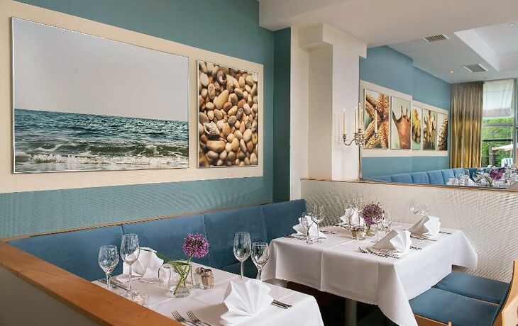 Innenansicht des Promenadenrestaurants Seestern mit gedeckten Tischen und Wandbildern.