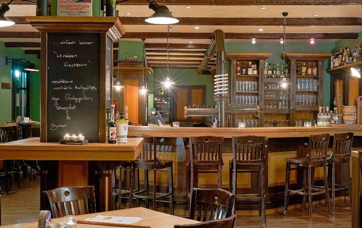 Gemütliche Bierkneipe mit Holzmöbeln und gut bestückter Bar im IFA Ferienpark Rügen.