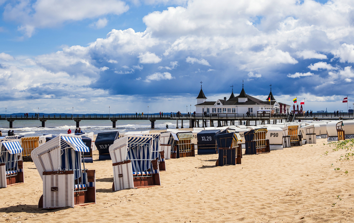 Strandkörbe und Seebrücke am Strand von Ahlbeck, Usedom, mit Wolken am Himmel.