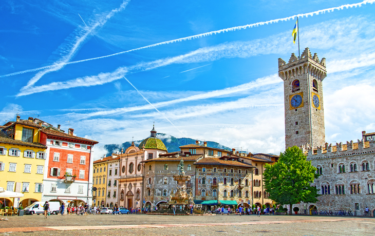 Historischer Platz mit bunt bemalten Gebäuden und Turm bei klarem Himmel.